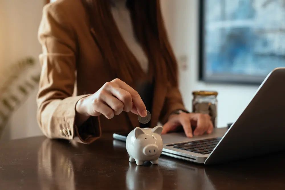 mUJER DEPOSITANDO MONEDAS EN UN VASO DE VIDRIO