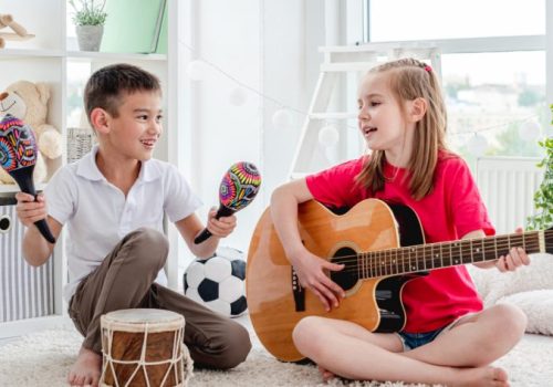 Niña y niño tocando la guitarra